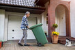© pikselstock - Senior man rolling garbage can
