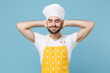 Relaxed young bearded male chef or cook baker man in apron white t-shirt toque chefs hat isolated on blue background in studio. Cooking food concept. Mock up copy space. Sleep with hands behind head.