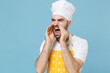 Dissatisfied bearded male chef or cook baker man in apron white t-shirt toque chefs hat isolated on blue background. Cooking food concept. Mock up copy space. Screaming with hands gesture near mouth.