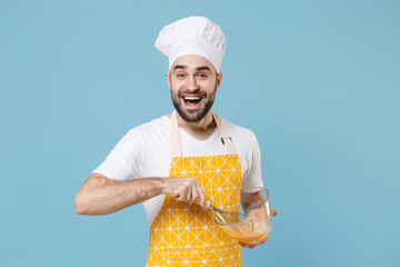 Excited young bearded male chef or cook baker man in apron white t-shirt toque chefs hat isolated on blue background in studio. Cooking food concept. Mock up copy space. Whipping beating eggs in bowl.