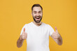 © ViDi Studio - Excited funny young bearded man guy in white casual t-shirt posing isolated on yellow wall background studio portrait. People sincere emotions lifestyle concept. Mock up copy space. Showing thumbs up.