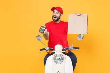 Wall Mural - Delivery man in red cap t-shirt uniform driving moped motorbike scooter hold craft paper packet with food isolated on yellow background studio Guy employee working courier Service quarantine concept