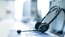 Call Center Operator Desktop. Close-up Of A Headset On A Laptop. Help Desk. Workplace Of A Support Service Employee. Headphones With A Microphone For Voip On A Computer Keyboard.