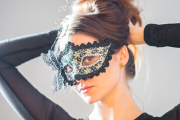 Woman in beautiful, black mask with white flowers, closeup studio portrait