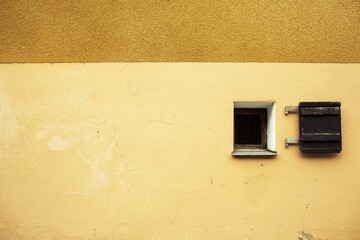 Canvas Print - Small window on a yellow concrete wall