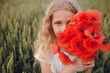 © Олег Кошевський - beautiful little girl with blond hair in a white dress in the background of a beautiful field. Girl with a bouquet of red poppies