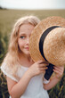 © Олег Кошевський - little girl with a straw hat. beautiful little girl with blond hair in a white dress in the background of a beautiful field. Girl with a bouquet of red poppies