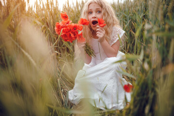 beautiful little girl with blond hair in a white dress in the background of a beautiful field. Girl with a bouquet of red poppies