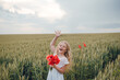 © Олег Кошевський - beautiful little girl with blond hair in a white dress in the background of a beautiful field. Girl with a bouquet of red poppies