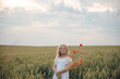 © Олег Кошевський - beautiful little girl with blond hair in a white dress in the background of a beautiful field. Girl with a bouquet of red poppies