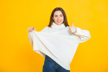 Slim woman in oversized sweater on yellow background. Weight loss