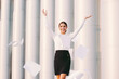 © Artem - Happy beautiful business woman in suit throw up papers away and smile outdoors. Cheerful young attractive girl celebrate success in office building. Successful female entrepreneur throw documents