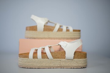 Closeup shot of modern white sandals on a gray background