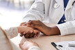 © insta_photos - African female doctor hold hand of caucasian woman patient give comfort, express health care sympathy, medical help trust support encourage reassure infertile patient at medical visit, closeup view.