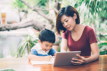Wall Mural - Son using digital tablet computer for study and learn to internet online with mother together, education from home, family recreation, mom teach boy and homework with technology, lifestyle concept.