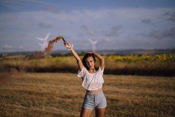 Sticker - Horizontal shot of a female posing with a smoke bomb on a background of fields and windmills