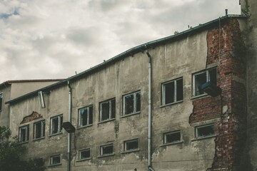 Sticker - Old worn down building with grey walls and bricks sticking out on one side with metal drains