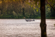 A Black And Gray Speedboat Navigates In Front Of The Tender Green Trees The Dnieper River In Kiev, Ukraine, At The Beginning Of Summer.