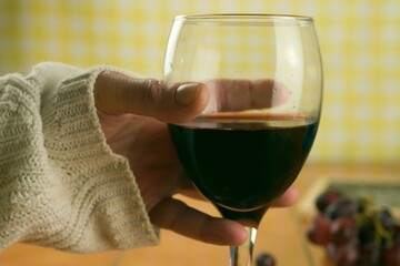 Wall Mural - Closeup shot of a man holding a glass of red wine on a blurred background