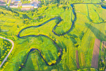 Wall Mural - Top aerial view of the natural rural landscape valley of a meandering river among green fields and forests.