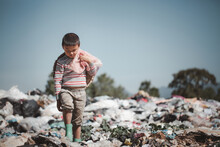 A Poor Boy Collecting Garbage Waste From A Landfill Site In The Outskirts .  Children Work At These Sites To Earn Their Livelihood. Poverty Concept.