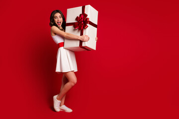 Canvas Print - Full length body size view of her she nice attractive cheerful wavy-haired girl holding in hands big white gift isolated on bright vivid shine vibrant red burgundy marsala maroon color background