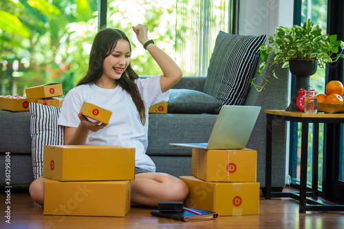 Freelance girl at home The product is being happily packed into a postal box after receiving an order from a customer, a business owner who works at home, a packaging office on the background.