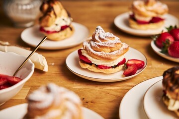 Poster - Closeup shot of delicious cream puff with strawberries and chocolate on a wooden table