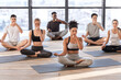 Young men and women in yoga studio practicing alternate nostril breathing exercises