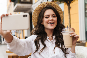 Poster - Portrait of woman taking selfie on cellphone while drinking milkshake