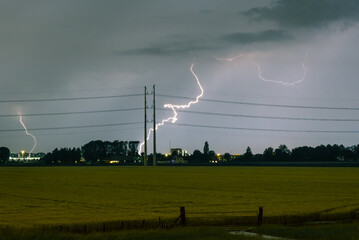 Wall Mural - lightning bolt hitting the ground near power lines during a severe thunderstorm