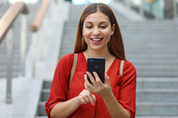 Wall Mural - Portrait of beautiful woman walking down the stairs holding her phone