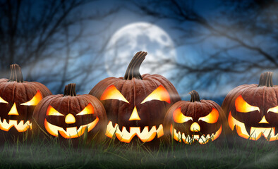 Wall Mural - five spooky halloween pumpkin, jack o lantern, with an evil face and eyes on the grass with a misty 