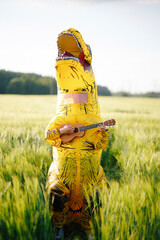 Two yellow and orange dinosaur dino tyrannosaurus running biting each other and having fun in green field. Shot from air. aerial shot. Dinosaur playing small guitar