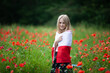 © Natallia - Blond girl wrapped in flag of Poland in the poppy field. Polish Flag Day. Travel and learn polish language concept.