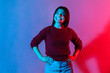 © khosrork - Happy emotions. Neon light portrait of joyful delighted woman in pullover looking up with wide toothy smile, cheerful grinning, laughing after hearing funny joke, anecdote. indoor studio shot isolated