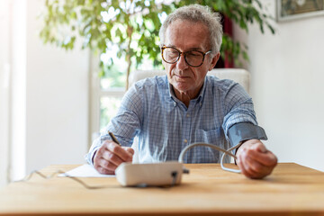 Senior man using medical device to measure blood pressure
