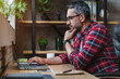 © InsideCreativeHouse - Side view shot of pensive young man sitting at home office and working on laptop