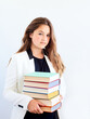 © zontica - Teenage student girl in white blazer holding in hands pile of books looking at camera over white background