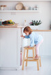 curious infant baby girl trying to reach the fruit on the table in the kitchen with the help of step stool