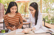 © PhotoJuthamat - Smiling Asian young woman sitting pointing studying examining, Tutor books with friends Young students campus helps friend catching up and learning. People learning education