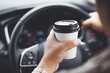 man hold paper cup coffee of hot in hand while driving a car