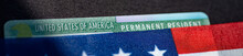 Fragment Of Permanent Resident Green Card Covered By Flag Of USA. Wide Photo.