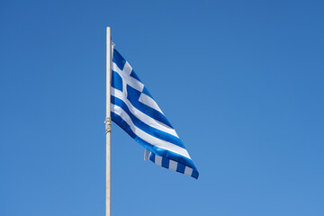 A flag of Greece against a clear blue sky. Copy space.