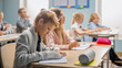 © Gorodenkoff - Elementary Classroom of Diverse Children Listening Attentively to their Teacher Giving Lesson. Brilliant Young Kids in School Writing in Exercise Notebooks, Taking Tests, Exams. Child With Broken Arm.