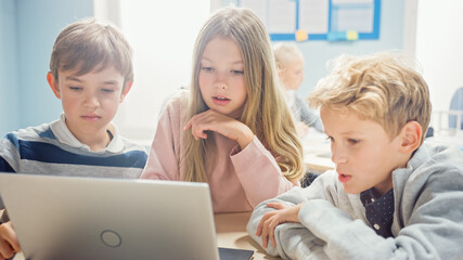 Wall Mural - elementary school classroom: diverse group of brilliant children using laptop computer for software 