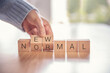 © oatawa - Woman hand arranging wooden cubes with NEW NORMAL word. Adapting to new life or business post-lockdown after coronavirus pandemic. Business with social distancing personal hygiene.