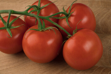 Branch with five tomatoes on a wooden board