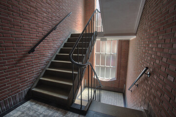 Stairwell in appartment building with brick wall, staircase antique old style complex with tall windows