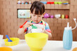 toddler girl pretend play food preparing role against cardboard blocks kitchen background